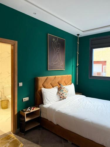 a bedroom with a green wall and a bed at Playa Surf House in Tamraght Ouzdar