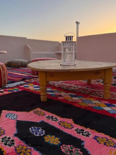 a wooden table sitting on a rug with a coffee table at Playa Surf House in Tamraght Ouzdar