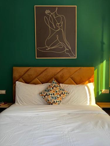 a bedroom with a white bed with a green wall at Playa Surf House in Tamraght Ouzdar