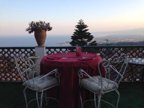 a table with a red table cloth and two chairs at Villa Greta Hotel Rooms & Suites in Taormina
