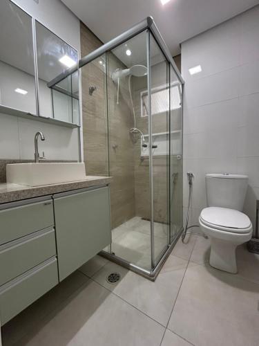 a bathroom with a glass shower and a toilet at Apto frente praia Gonzaguinha in São Vicente
