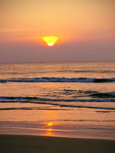 a sunset on the beach with the sun setting at Curly Hostel Negombo in Negombo