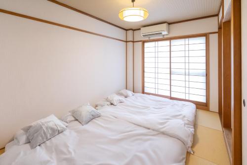 a large white bed in a room with a window at 住舎高見 in Osaka