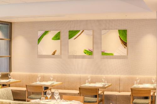 a dining room with tables and chairs and paintings on the wall at Stadium City Hotel Nagasaki in Nagasaki