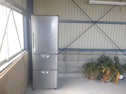 a stainless steel refrigerator in a room with plants at 岐阜羽島の隠れ家 古民家cocone in Hashima