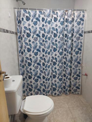 a bathroom with a toilet and a blue and white shower curtain at Lauquen in Puerto Deseado