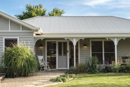 a house with a porch with a chair in the yard at Kookaburra Cottage - 10 minutes from Mount Gambier CBD in Yahl