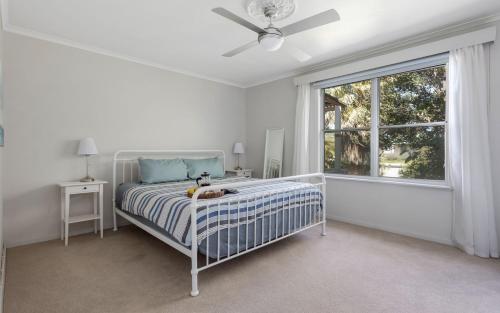 a white bedroom with a bed and a window at Seaside Escape - 4 Brittain St, Port Elliot in Port Elliot