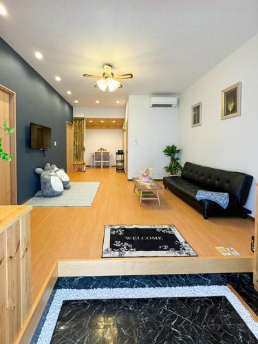 a living room with a black couch and a table at 大阪一軒家 最大8名 WiFi 粉浜駅8分 関西空港直通 天下茶屋電車2分 in Osaka