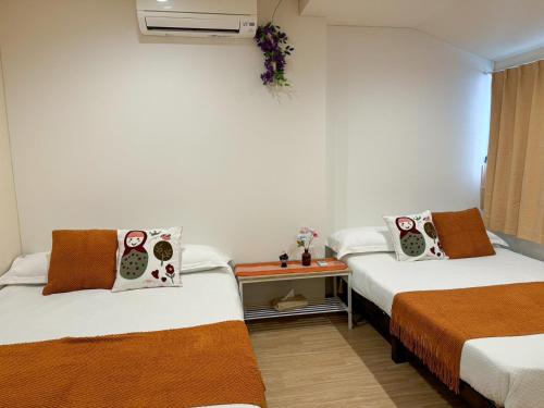 a room with two beds and a small table at 大阪一軒家 最大8名 WiFi 粉浜駅8分 関西空港直通 天下茶屋電車2分 in Osaka