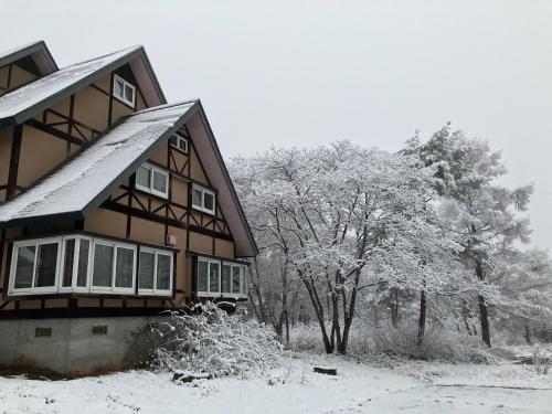 a house covered in snow with trees in the background at Cottage Alice in Hachimantai