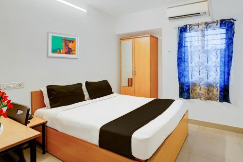 a bedroom with a bed and a desk and a window at Super Hotel O Valasaravakkam Near Chandra Metro Mall in Chennai