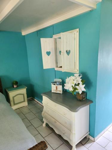 ein Schlafzimmer mit blauen Wänden und einer Kommode mit Blumen darauf in der Unterkunft Droomstudio seru coral 32 in Willemstad