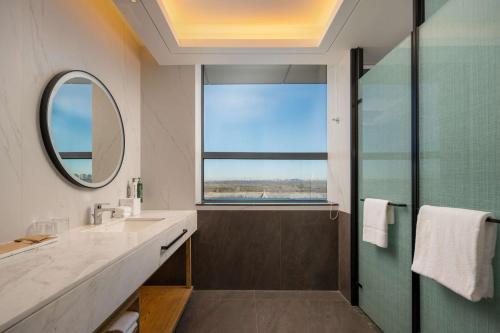 un bagno con doccia, lavandino e specchio di Hilton Garden Inn Ordos Kangbashi a Ordos