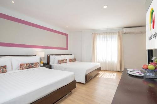 a hotel room with two beds and a table at Hotel De Bangkok in Bangkok