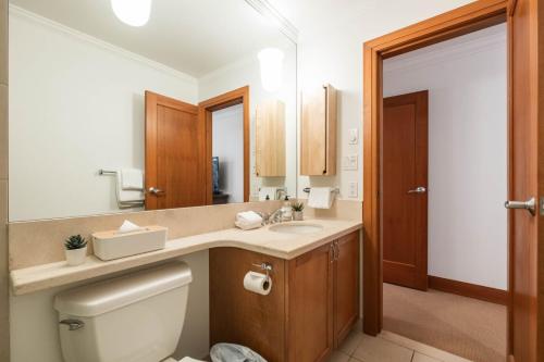 een badkamer met een toilet, een wastafel en een spiegel bij Montebello 4877 by Outpost Whistler in Whistler