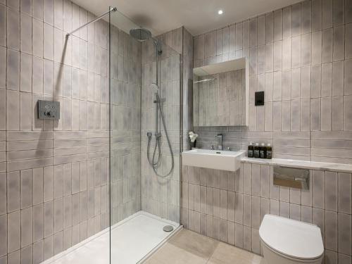 a bathroom with a shower and a toilet and a sink at The Spitalfields Works by Urban Rest in London