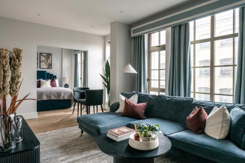 a living room with a blue couch and a bed at The Spitalfields Works by Urban Rest in London