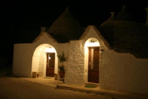 um edifício branco com duas portas à noite em La Trullesa Holiday em Alberobello