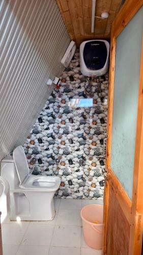 a bathroom with a toilet and a tv on the wall at Eva Cabins in Dalhousie