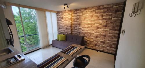 a living room with a couch and a brick wall at Apartamento moderno Miravalle in Popayan