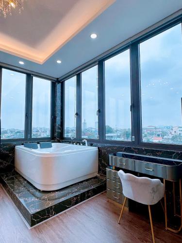 a large bath tub in a room with windows at Royal Homestay And Coffee in Thôn Lại Thê