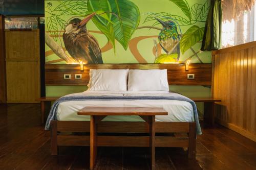 a bedroom with a bed and a painting of birds at Amazon Muyuna Lodge - All Inclusive in Paraíso