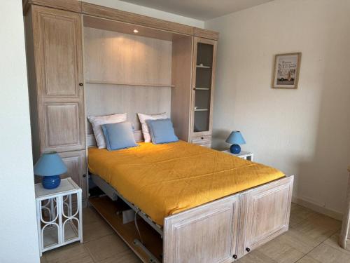 Cette chambre comprend un grand lit avec des draps jaunes et des oreillers bleus. dans l'établissement Studio moderne 2* avec balcon, centre St Palais, parking sécurisé - FR-1-738-38, à Saint-Palais-sur-Mer