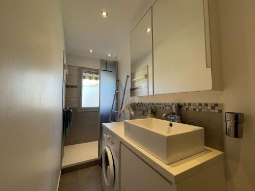 une salle de bain avec un lavabo et une machine à laver dans l'établissement Appartement T2 Lumineux avec Parking Privatif - Centre-Ville - FR-1-308-203, au Lavandou
