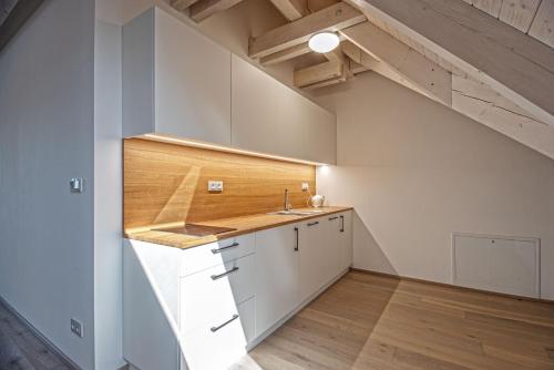 an attic kitchen with white cabinets and a sink at Usedlost U lípy Blatiny in Sněžné