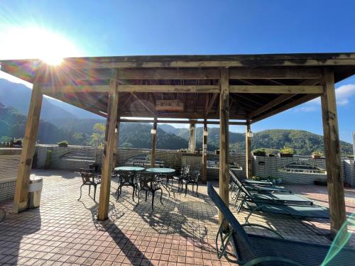 a patio with tables and chairs and the sun shining at Ginkgo Hotel in Lugu