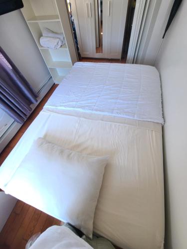 a bed with white sheets and pillows in a room at Nice rooms Woodside in Queens