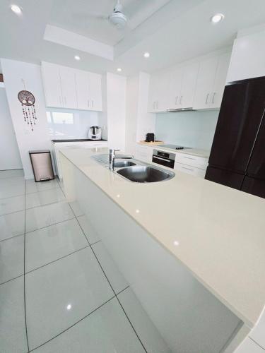 a white kitchen with a sink and a counter at Skyview 2 bathroom Sub-Penthouse Harbour Views in Darwin