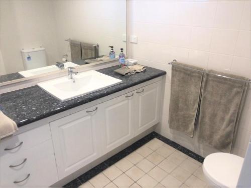 a bathroom with a sink and a mirror and a toilet at Frangipani 206 beachfront apartment in Hamilton Island