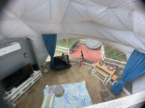 a man sitting in a living room in a tent at Isla Riviere Dome Tent Luxury Glamping , Laguna in Salangbato