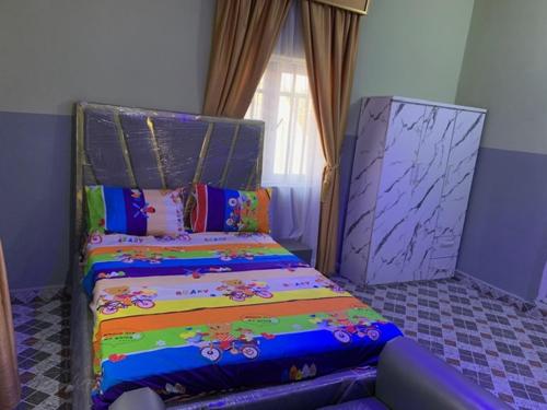 a bedroom with a bed with colorful sheets and a window at Oxford Villa in Nnewi