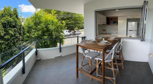 a balcony with a wooden table and chairs and a kitchen at Location, location, location - spacious apartment in Brisbane