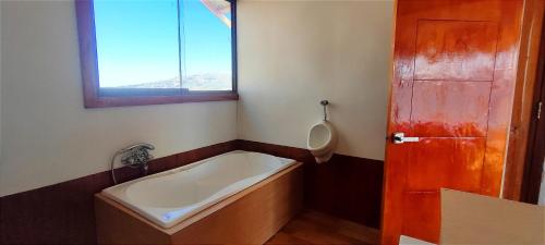 a bathroom with a tub and a urinal and a window at Titicaca Vista Atardecer in Puno