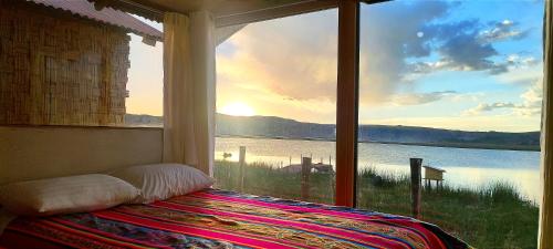 a bedroom with a large window with a view of the water at Titicaca Vista Atardecer in Puno