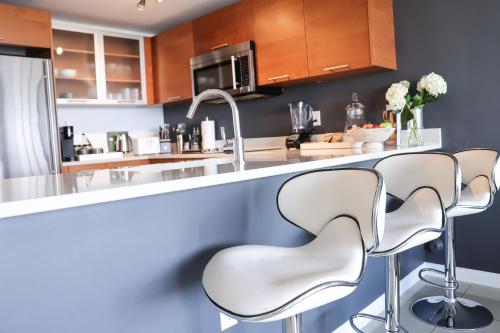 a kitchen with three white chairs at a counter at Luxury Midtown Miami Apartment in Miami