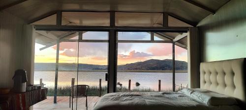 a bedroom with a large window with a view of the water at Titicaca Vista Atardecer in Puno