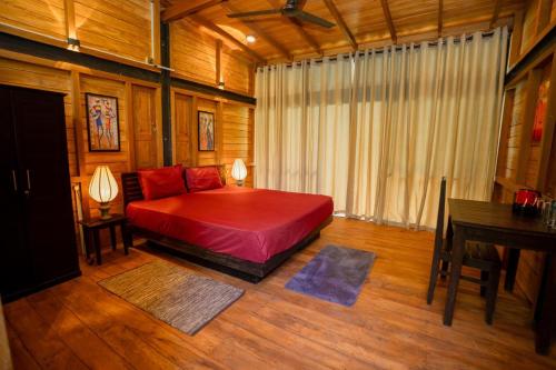a bedroom with a red bed in a room with a desk at Eliyanth Udawalawe in Udawalawe