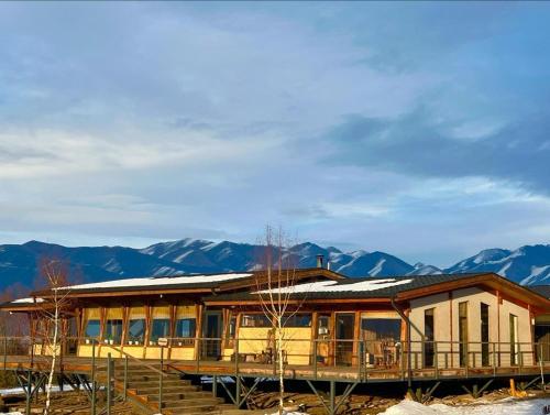 a house with a deck and mountains in the background at Kemin Guest House in Tar-Suu