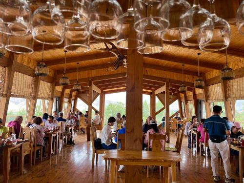 a group of people sitting at tables in a restaurant at Kemin Guest House in Tar-Suu