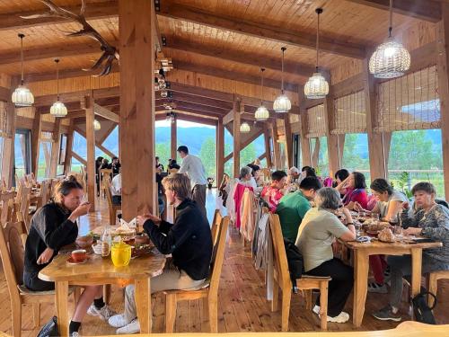a group of people sitting at tables in a restaurant at Kemin Guest House in Tar-Suu