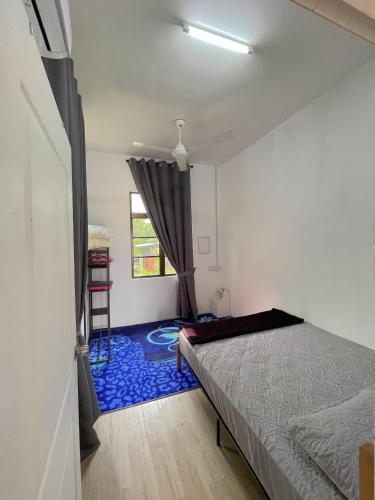 a bedroom with a bed and a blue carpet at Teratak Zaa D’Homestay in Kota Bharu