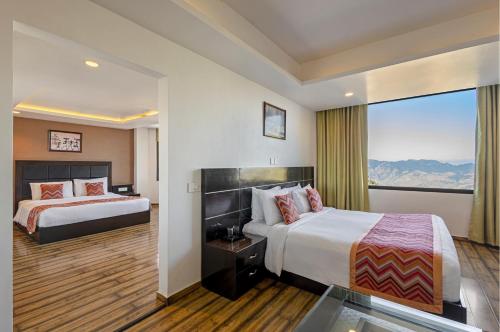 Una habitación de hotel con dos camas y una gran ventana. en Sterling Kufri, en Kūfrī