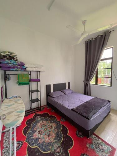 a bedroom with a bed and a chair and a rug at Teratak Zaa D’Homestay in Kota Bharu