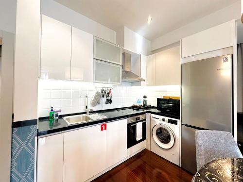 a kitchen with white cabinets and a washer and dryer at Somerset City Centre Atyrau in Atyraū