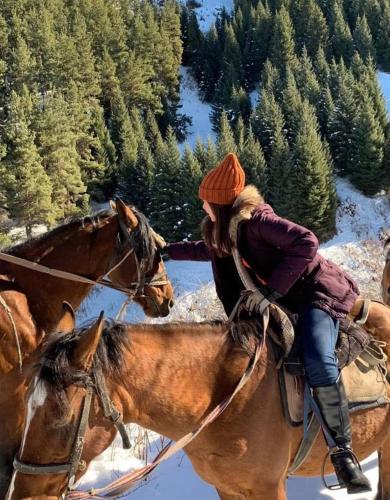 a woman is riding a horse in the snow at Kemin Guest House in Tar-Suu